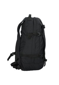 Mochila negra de tela con correas ajustables, hebillas laterales y una superficie texturizada. Presenta un diseño aerodinámico y un respaldo acolchado para mayor comodidad.
