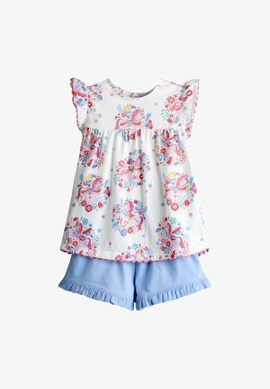 Haut blanc sans manches avec imprimé licorne rose et motifs floraux, assorti à un short bleu clair à volants.