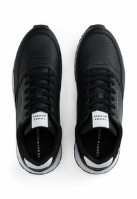 Schwarze sportliche Sneakers mit perforiertem Lederobermaterial, tonal abgesteppt und weißen Akzenten an Ferse und Zunge. Schnürdesign.