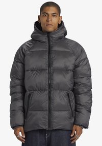 Ullared jacka i mörkgrått, med dragkedja framtill, huva och sidofickor. Tillverkad av lätt, texturerat tyg med quiltat mönster.