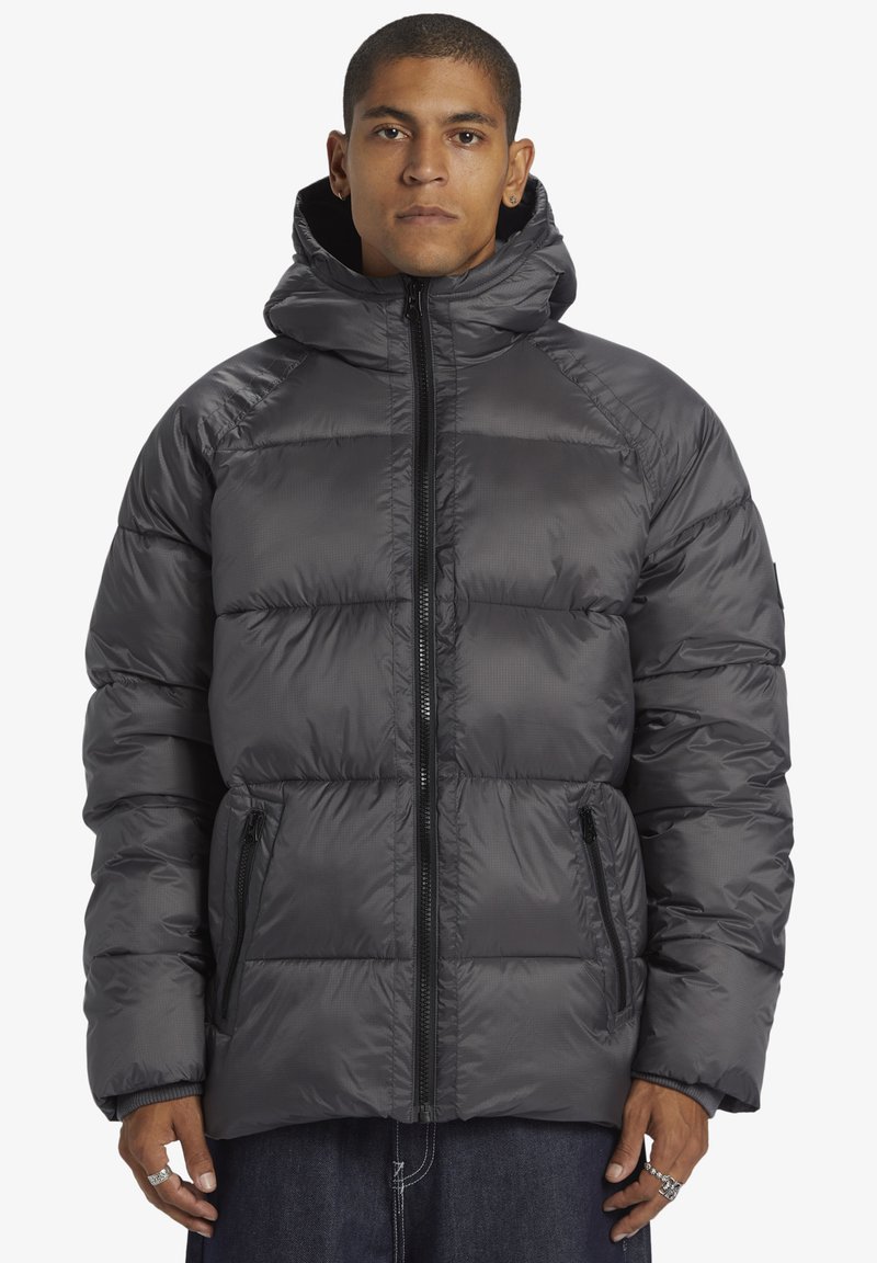 Ullared jacka i mörkgrått, med dragkedja framtill, huva och sidofickor. Tillverkad av lätt, texturerat tyg med quiltat mönster.