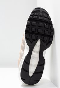 Tenisky s texturovanou černou gumovou podrážkou, s lehkým béžovým a bílým svrškem z hladkých a vrstvených materiálů.