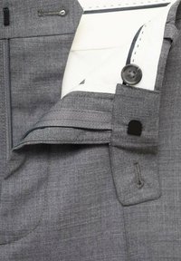 Pantaloni gri cu o textură de material neted, închidere cu fermoar, detalii cu nasturi și o căptușeală albă cu accente de cusătură.