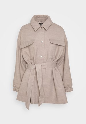 Beige wollen jas met ceintuur, grote voorzakken met klep, drukknoopsluiting, elastische manchetten en een brede kraag.