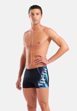 Schwarze Badeshorts mit blauem Grafikdesign auf der linken Seite, aus leichtem Material gefertigt. Eng anliegende Form, elastischer Bund und glatte Textur.