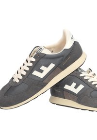 Coppia di scarpe da corsa grigie e crema con lacci bianchi e logo, realizzate in materiali mesh e pelle scamosciata, sovrapposte su uno sfondo bianco.
