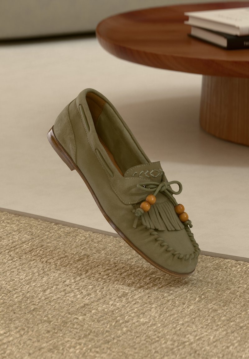 Mocassin vert olive avec détails en franges, perles décoratives et broderie. Dispose d'une semelle en cuir et de découpes latérales pour la respirabilité.