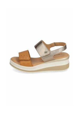 Sandale compensée avec bride métallique dorée à la cheville, bride en cuir fauve à l'avant-pied avec découpes carrées, et semelle beige en plusieurs couches.