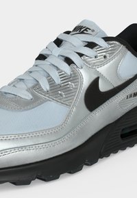 Ασημί και ανοιχτό μπλε αθλητικό παπούτσι Nike Air Max με μαύρο λογότυπο swoosh και μαύρη σόλα, δεμένο και από την πλευρά.