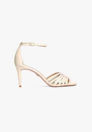 Beige High-Heel-Sandale mit Knöchelriemen und Schnalle, offenem Zehenbereich mit mehreren dünnen, überkreuzten Riemchen und einem mittelhohen Stiletto-Absatz.