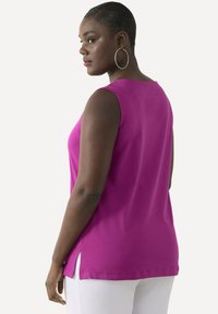 Mouwloos, roze top met een ronde halslijn en zijsplitten. Zacht materiaal, normale pasvorm, gladde textuur en een effen kleur ontwerp.