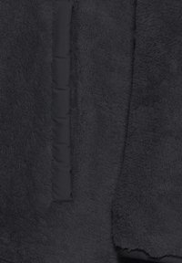 Schwarze Fleecejacke mit strukturierten Oberflächen, glattem Stoffeinsatz und kontrastierenden Nähten. Locker geschnitten für hohen Tragekomfort.