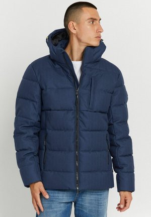 Navy blue puffer jacket with a zip-up front, hood, textile exterior, and a chest pocket. Features a contrasting black zipper and stitched pattern.