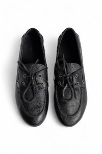 Zapatos de cuero negro con un acabado texturizado, puntera redonda y sistema de cordones con dos ojetes. Presenta detalles en tono dorado y una suela antideslizante.