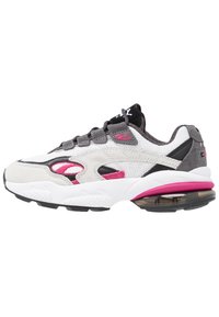 Baskets de sport blanches, grises et roses avec des panneaux en mesh et en daim, des lacets noirs et une section de semelle à coussin d'air transparent.