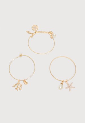 Tre armbånd i guldfarve med havtema-vedhæng: sanddollar, fjer, perle; koralgren og muslingeskal; søstjerne og perle.