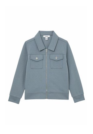 Lyseblå lynlåstrøje lavet af blødt stof. Har en stor krave og to frontlommer med trykknapper. Lange ærmer med ribbede manchetter.