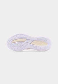 Σόλα λευκού αθλητικού παπουτσιού με μπεζ πέλματα πρόσφυσης και υφή στο πέλμα πάνω σε απλό φωτεινό φόντο.