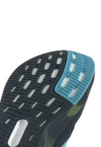 Semelle de sneaker noire et turquoise en caoutchouc texturé, avec des rainures, des découpes circulaires et des accents verts mouchetés.