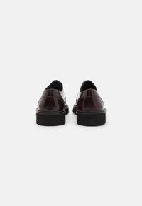 Scarpe in pelle borgogna con finitura lucida, punta rotonda e suola in gomma nera spessa, con dettagli di cucitura minimal.