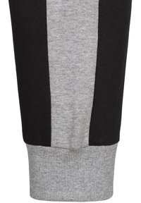 Svarta och grå sweatpants har en ribbad grå mudd med kontrasterande sidopanels. Texturen är mjuk och är gjord av en bomullsblandning.