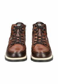 Botas de tobillo de cuero marrón con cordones negros, una suela media blanca y una suela exterior texturizada negra. Presentan cremalleras para facilitar el calzado y un diseño de costura único.