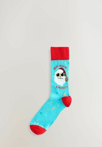 Calzini turchesi con risvolto e punta rossi. Presentano un'immagine di Babbo Natale con occhiali da sole, la scritta "ENERGIA DI BIG NICK" e stelle dorate.