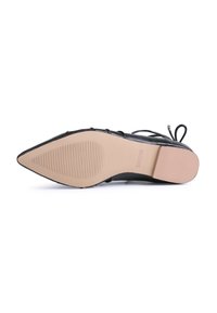 Zapato negro de punta afilada con parte superior de piel lisa. Presenta una suela de goma beige con estrías para mayor tracción y cordones finos en el talón.