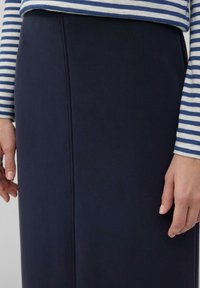 Navyblauwe rok met een gladde textuur en een rechte silhoeet, gecombineerd met een gestreepte, langarm top in wit en blauw.