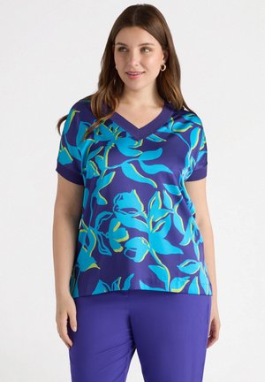 T-shirt à manches courtes en bleu marine avec un motif floral teal vif. Doté d'un col en V et de finitions côtelées. Associé à un pantalon violet uni.