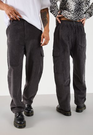 Gray corduroy pants featuring a relaxed fit, elastic waistband, and side pockets. Paired with black shoes, showcasing a textured fabric.