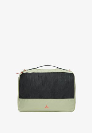 Lichtgroene opbergkubus met zwarte gaasvoorkant, rode ritsuiteinden en handvat aan de bovenkant, gebruikt voor het organiseren van reisartikelen.