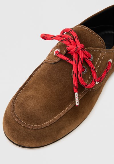 Smeđi antilop cipele s crvenim i crnim uzorcima vezica, srebrnim rupicama i kontrastnim šavovima duž ruba. Dizajn s zaobljenim prstom.