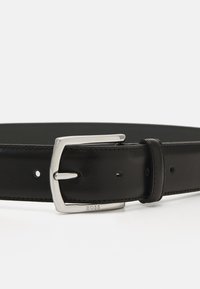 Ceinture en cuir noir avec une boucle en métal argenté, présentant une texture lisse, sept trous pour le réglage de la taille, et le logo 'BOSS' sur la boucle.