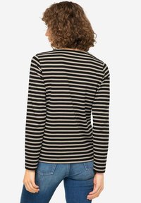 Lange mouw shirt in zwart en beige met strepen, gemaakt van zachte stof. Beschikt over een ronde halslijn en een aansluitende pasvorm, gecombineerd met denim jeans.