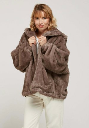 Veste à capuche en fausse fourrure de couleur marron doux, dotée d'une fermeture éclair à l'avant, de manches surdimensionnées et d'une coupe décontractée. Texture lisse et poches latérales.