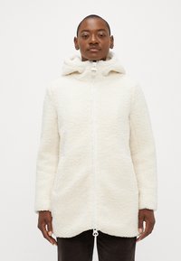 Veste en polaire blanche avec capuche, dotée d'un zip frontal complet, d'une texture douce et d'un ourlet arrondi. Manches longues et détails minimalistes.