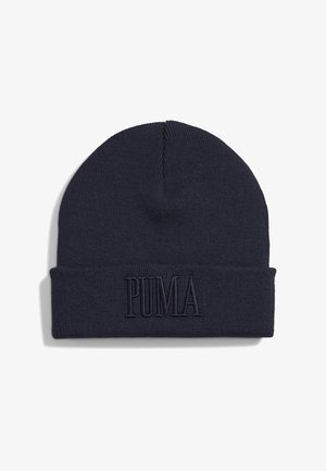 Tamsiai mėlynas megztas skrybėlė su sulankstomu kraštu, kuriame yra reljefinė „PUMA“ logo tos pačios spalvos. Minkšta tekstūra, suapvalintas viršus.