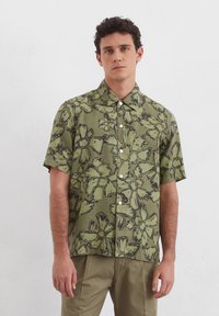 Korte mouwen shirt van groene katoen met zwart bloemenprint, met een kraag en een sluiting met knopen aan de voorkant. Soepele textuur en losse pasvorm.