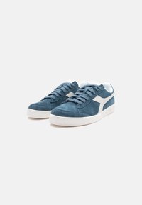 Dark blue suede sneakers with white accents, round toe, white rubber sole, and lace-up design. Textured upper with stitched detailing.