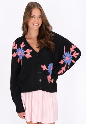 Zwarte gebreide cardi met een diepe V-hals, voorzien van kleurrijke bloemenborduursels in roze en blauw, en zwarte knopen aan de voorkant.