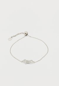 Λεπτό ασημένιο βραχιόλι με ρυθμιζόμενο στρογγυλό κούμπωμα και κεντρικό γοργόνα σε σχήμα φιόγκου διακοσμημένο με μικρούς κρυστάλλους.