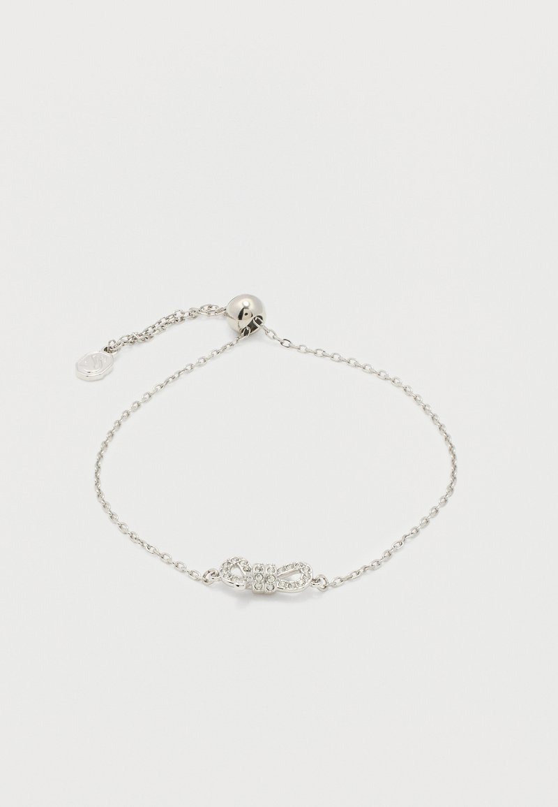 Λεπτό ασημένιο βραχιόλι με ρυθμιζόμενο στρογγυλό κούμπωμα και κεντρικό γοργόνα σε σχήμα φιόγκου διακοσμημένο με μικρούς κρυστάλλους.