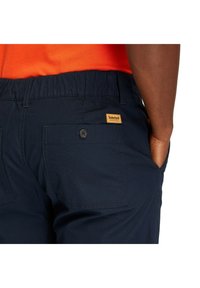 Marina blå shorts i andningsbart tyg, med elastisk midja, två bakfickor, knäppning med knapp och en Timberland logotyp på lappen.