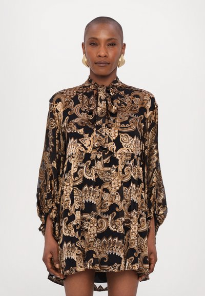 Blusa negra con un patrón de paisley dorado, que presenta un escote alto, mangas largas y un diseño fruncido para una silueta fluida.