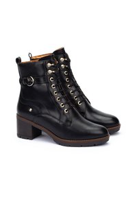 Botas de cuero negro hasta el tobillo con punta redondeada, cordones en la parte delantera y un broche lateral. Cuentan con una suela texturizada y un tacón medio para mayor estabilidad.
