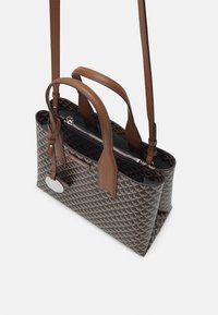 Strukturovaná taška přes rameno s geometrickým vzorem v hnědé a béžové barvě. Má kožené popruhy a stříbrnou visačku s logem. Zapínání na zip v horní části.