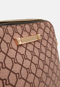 Hnědé látkové pouzdro s vzorem a zlatým zipem, na přední straně s obdélníkovou zlatou štítkem vyrytou s textem "River Island".