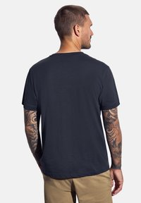 Tmavě modré bavlněné tričko s klasickým kulatým výstřihem, krátkým rukávem a volným střihem. Hladká textura bez viditelných vzorů nebo dekorací.