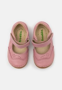 Růžové kožené baleríny Mary Jane se zapínáním, kulatou špičkou, perforovaným květinovým vzorem, hnědou stélkou a prošívanými detaily na podrážce.